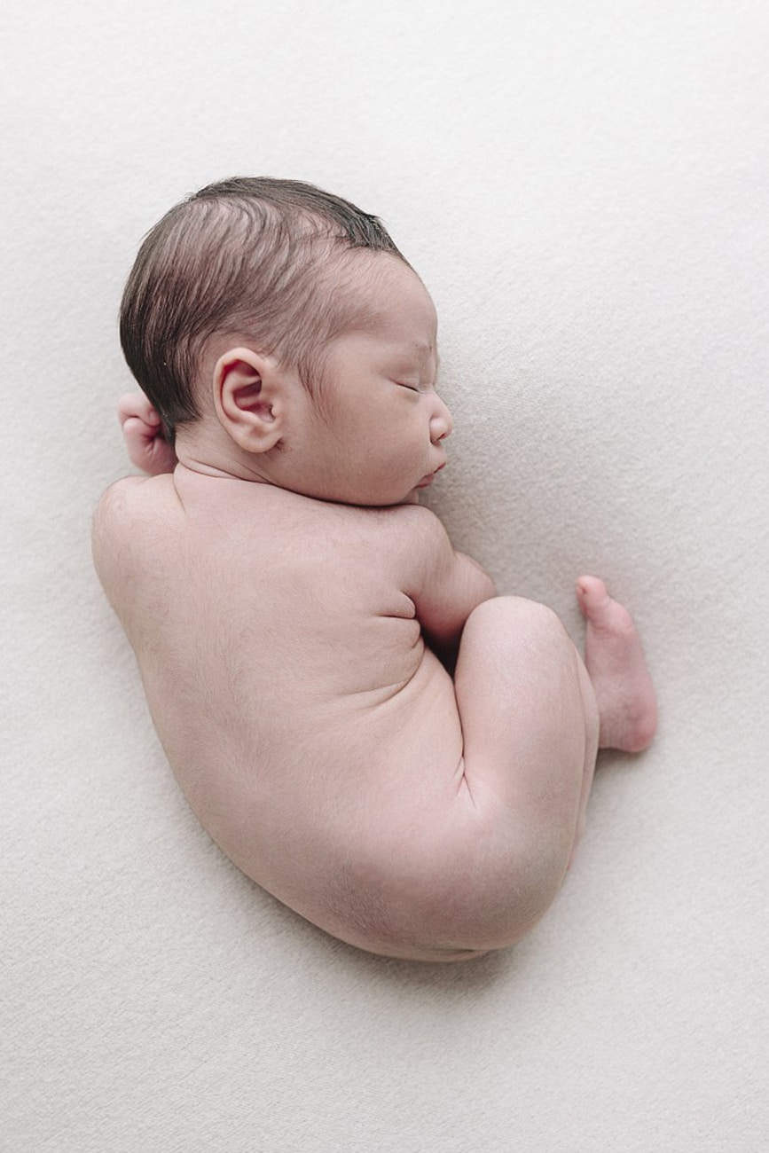 Naked baby sleeping in a ball