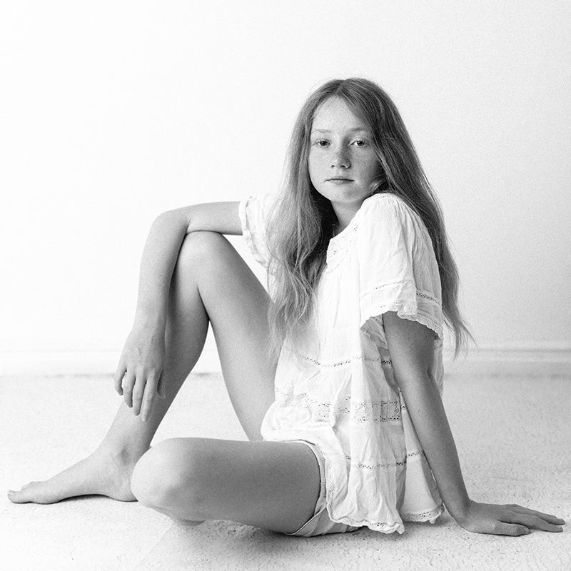 A girl sitting on the floor, photographed in black and white