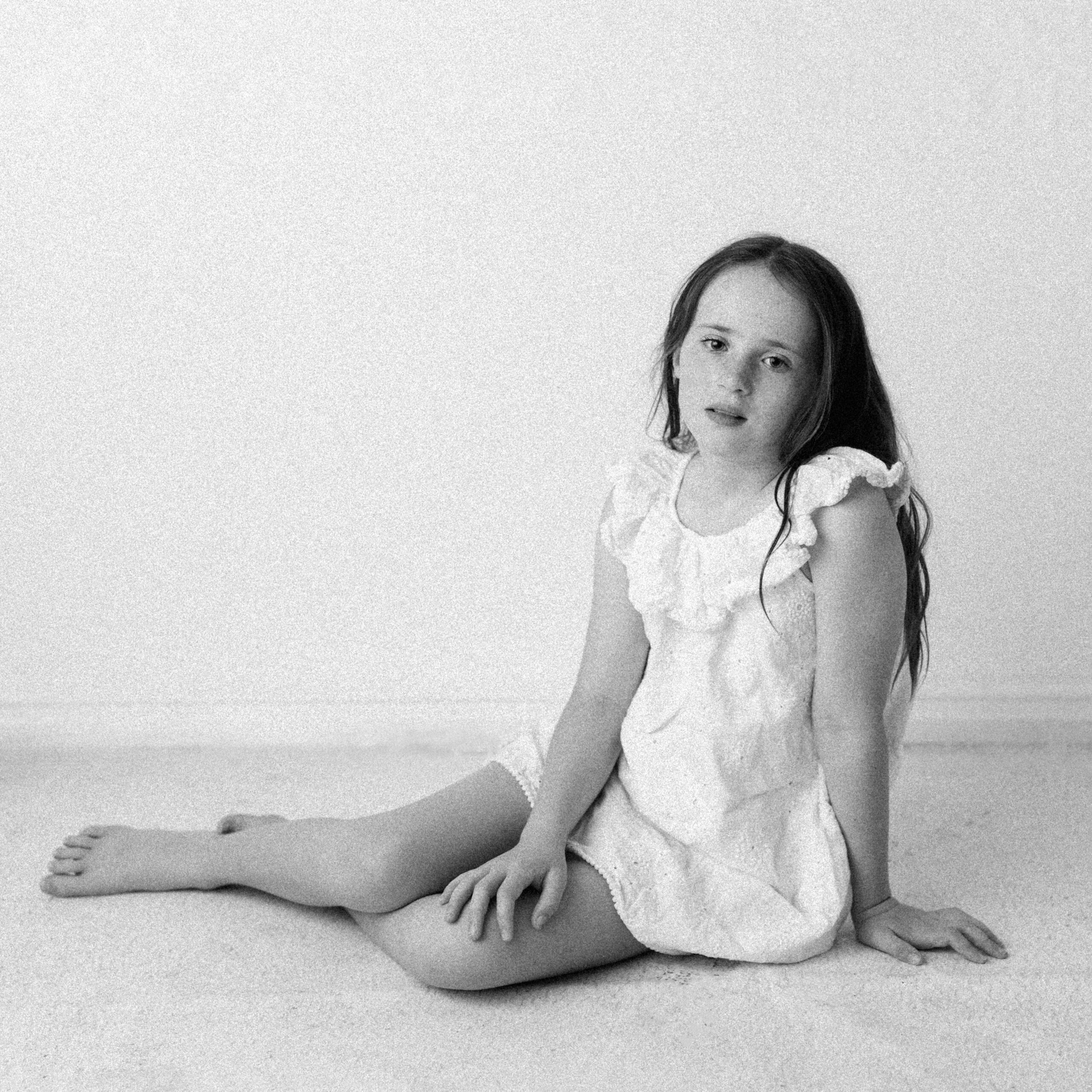 A girl sitting on the floor, photographed in black and white