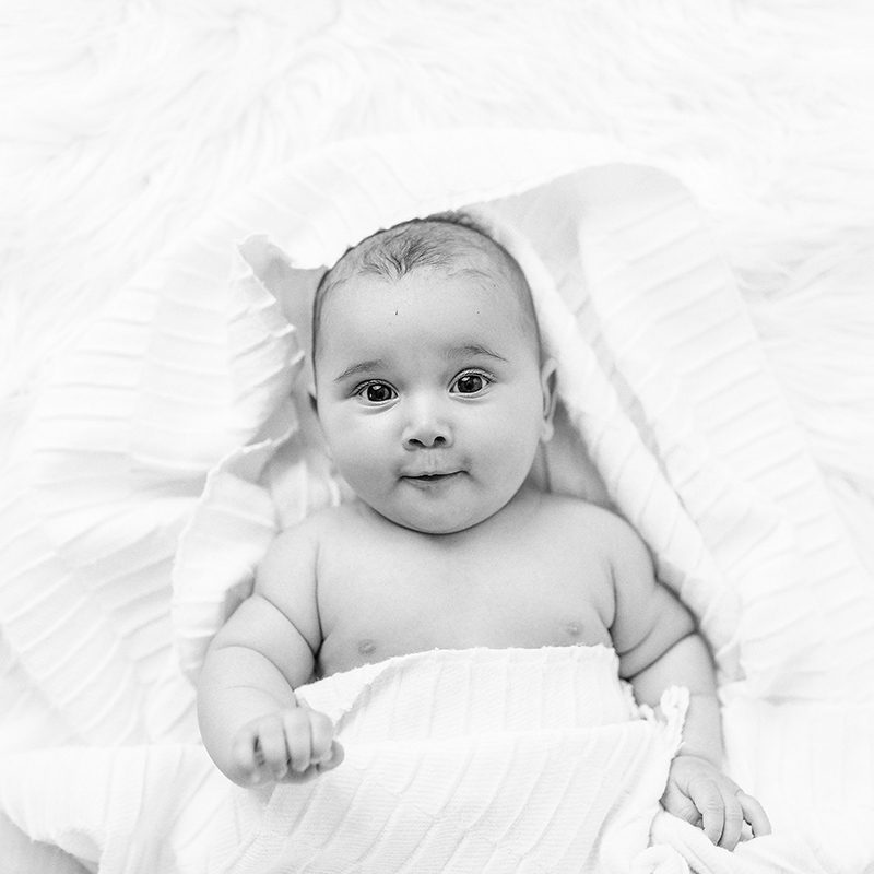A baby lying down in blankets that cover her body