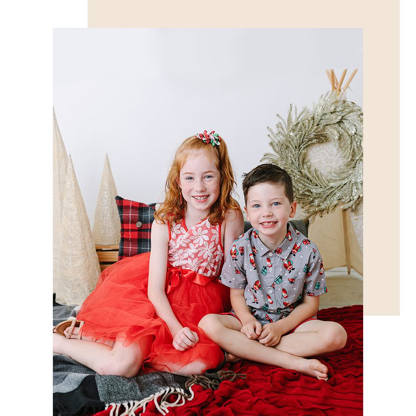 Brother and sister sitting amongst christmas decorations