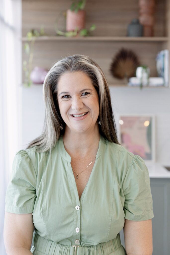 Friendly professional headshot showing woman standing in relaxed pose, smiling naturally.