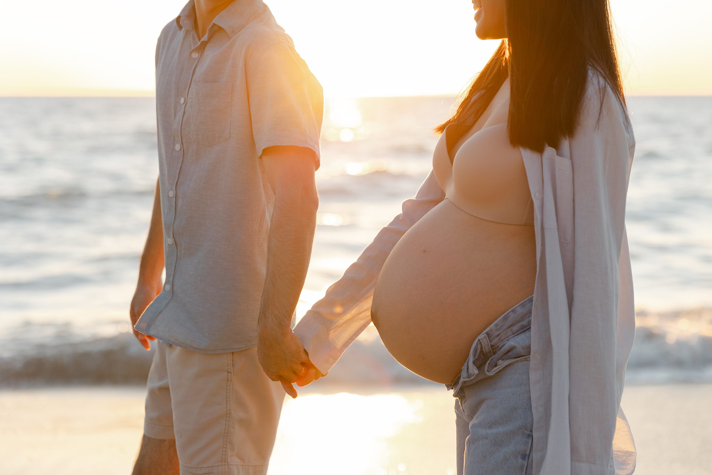 Hands of both parents-to-be resting on baby bump during an intimate maternity moment captured in Perth