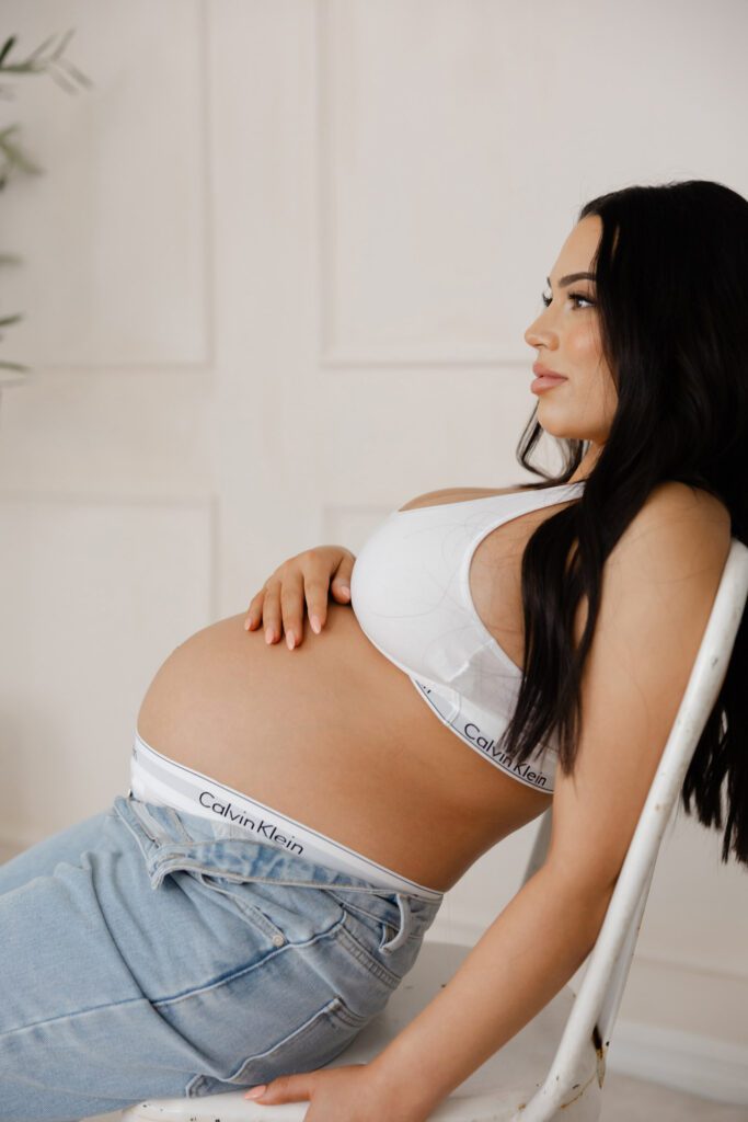 Pregnant woman cradling belly during indoor maternity photoshoot in Perth.